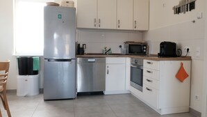 Una cuina moderna amb electrodomèstics d'acer inoxidable, armaris blancs i un finestral que aporta llum natural.