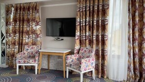 A room with two floral-patterned chairs, a small table, and a flat-screen TV mounted on the wall. - Senator Boutique Hotel Baku (Baku)