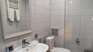 A bathroom with a large mirror, a sink, a toilet, and a shower area. - Senator Boutique Hotel Baku (Baku)