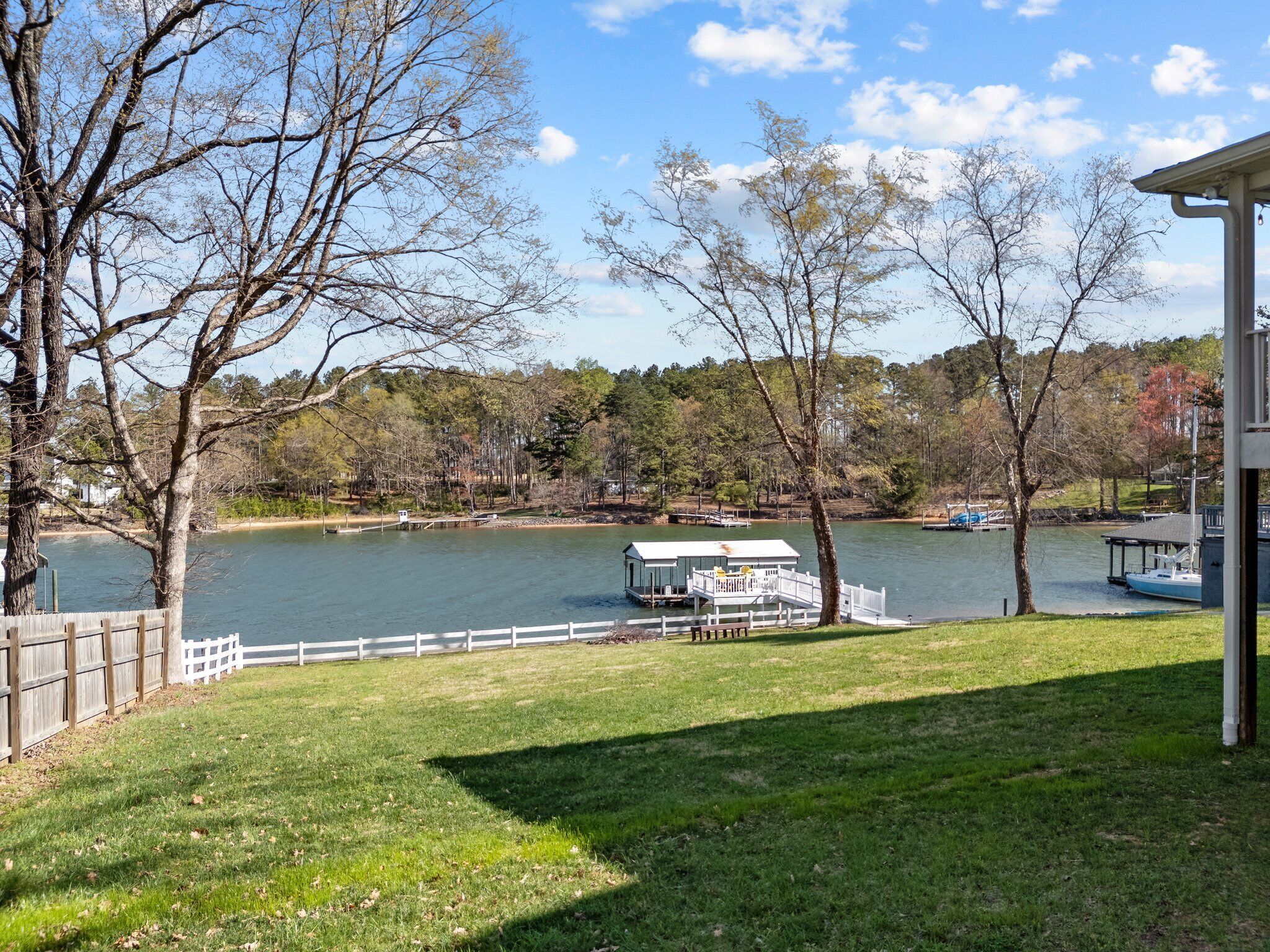 Una proprietà sul lago con molo, area verde e un edificio con facciata bianca.