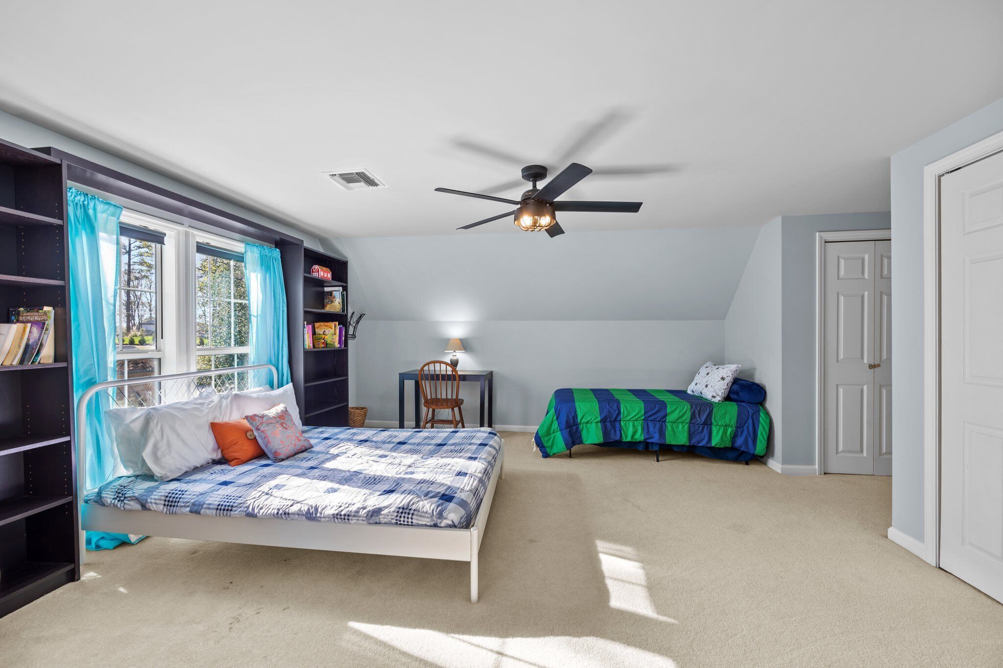 Une chambre à coucher avec un lit, un bureau, une chaise et un ventilateur de plafond.