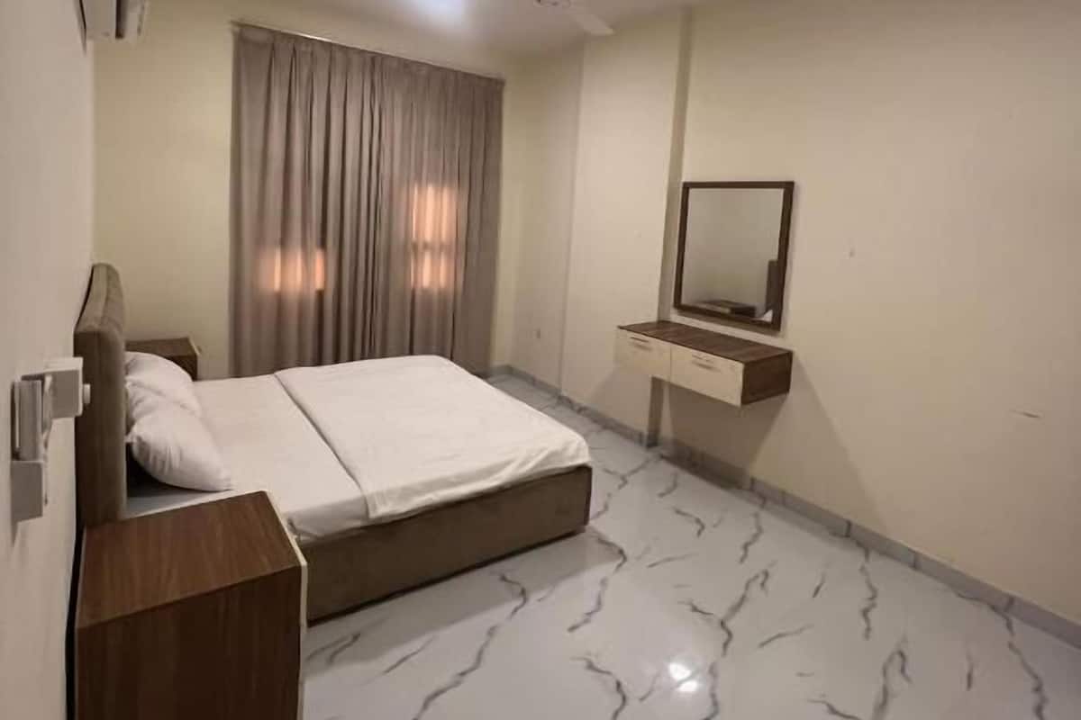 A bedroom with a bed, a nightstand, a mirror, and a ceiling fan.