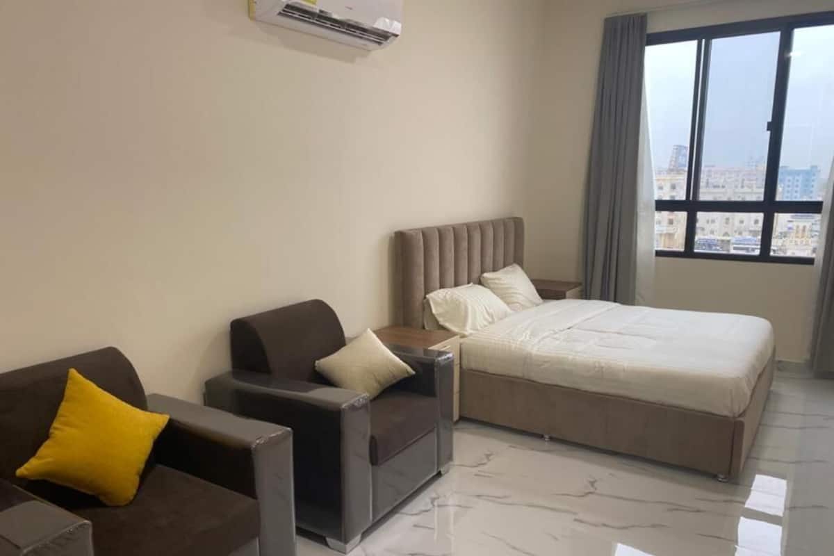 A hotel room with a bed, a sofa, and a chair.