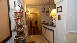 A hallway with a decorative Christmas tree, a reception desk, and framed pictures on the walls.