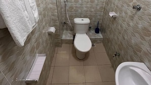 Ein kleines Badezimmer mit Toilette, Bidet, Waschbecken und Handtuchhalter.