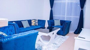 Ein modernes Wohnzimmer mit einer blauen Sofagarnitur, einem weißen Couchtisch und einem weißen Beistelltisch.