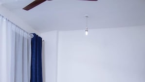 Ein hölzernes Bett mit weißer Bettwäsche in einem Zimmer mit weißen Wänden und einem Deckenventilator.