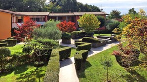 A well-maintained garden with neatly trimmed hedges and a pathway leading to a building with a tiled roof.