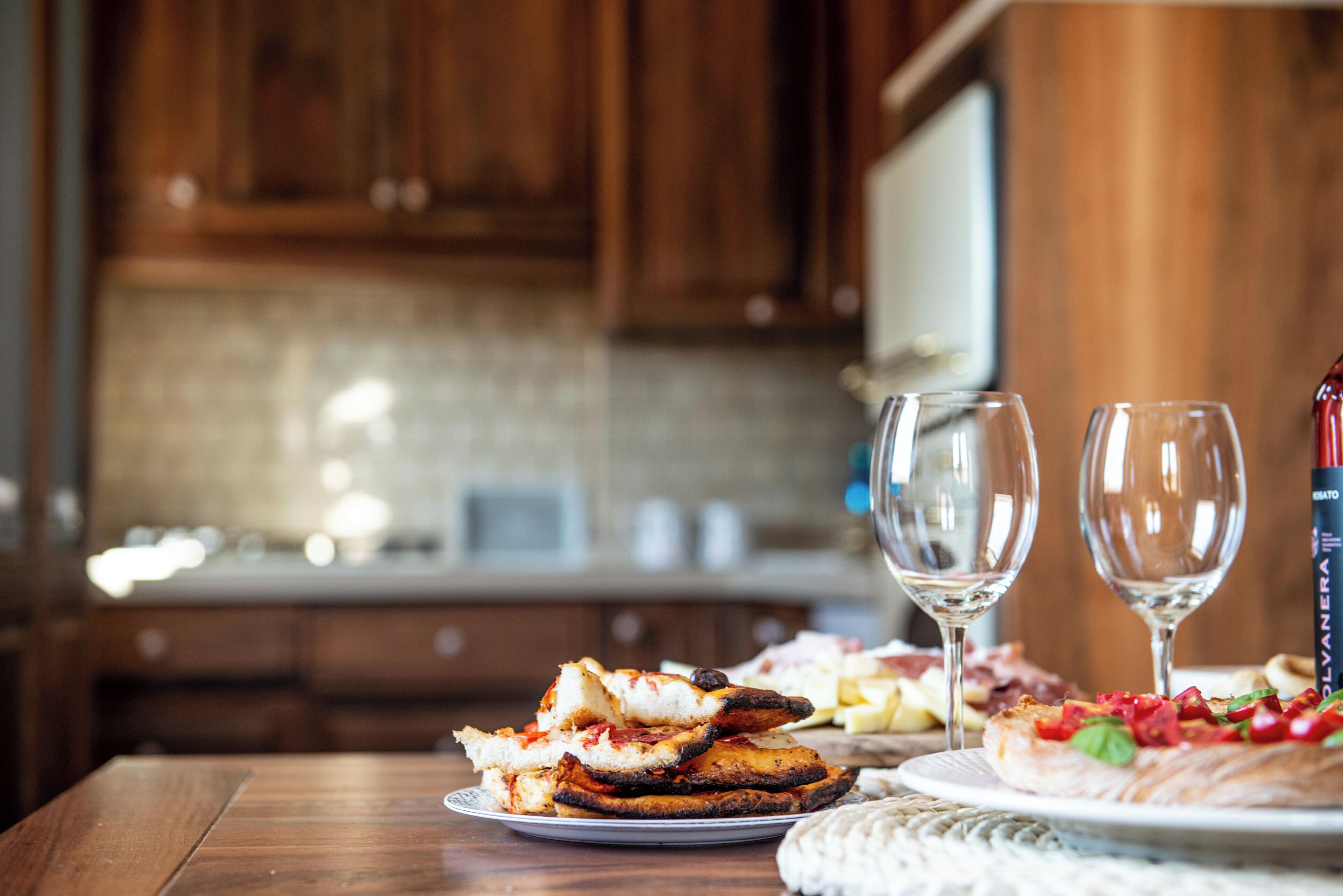 A wooden table with pizza and two glasses of white wine.