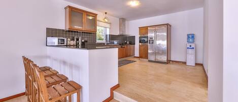 A modern kitchen with wooden cabinets, a central island, and a stainless steel refrigerator.