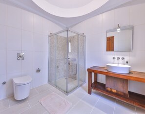 A modern bathroom with a glass-enclosed shower, a white toilet, and a wooden vanity with a sink. - Villa Nane (Kas)