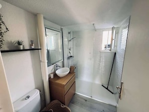 Un baño pequeño con inodoro, lavamanos y ducha.