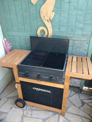 A portable camping stove with a control panel, placed on a wooden table. - MerBella Villa Comfort and Pool (Valras-Plage)