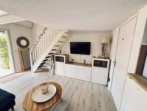 A modern interior with a staircase, a flat-screen TV, and a dining area with a round table. - MerBella Villa Comfort and Pool (Valras-Plage)