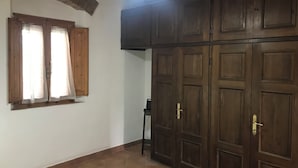A room with a large wardrobe, a ceiling fan, and a window with curtains.