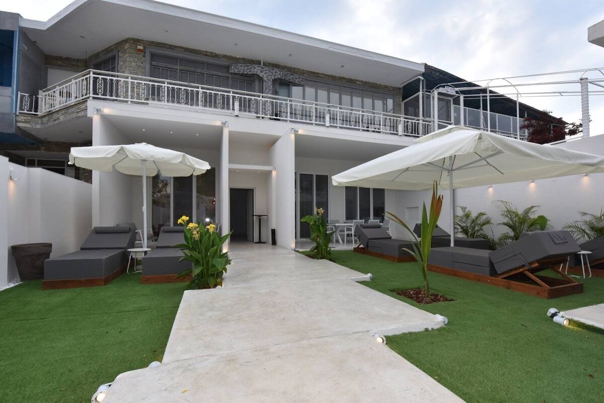 Eine moderne Außenpatio mit Liegestühlen, Sonnenschirmen und künstlichem Rasen.