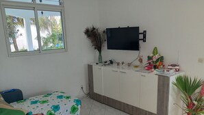 Huoneessa on sänky, työpöytä, televisio ja ikkuna, josta avautuu näkymä puita kohti.
