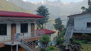 A two-story building with a red roof, a staircase, and a view of snow-capped mountains in the background. - Namami Kedara Resort (Ukhimath)