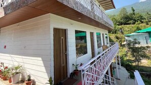 A two-story building with a balcony, potted plants, and a staircase leading to the upper level. - Namami Kedara Resort (Ukhimath)