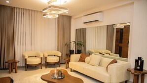 A modern living room with a beige sofa, two armchairs, a coffee table, and a wooden side table. - little hideaway (Dar es Salaam)