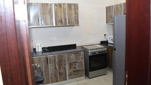 A compact kitchen with wooden cabinets, a stove, and a refrigerator.