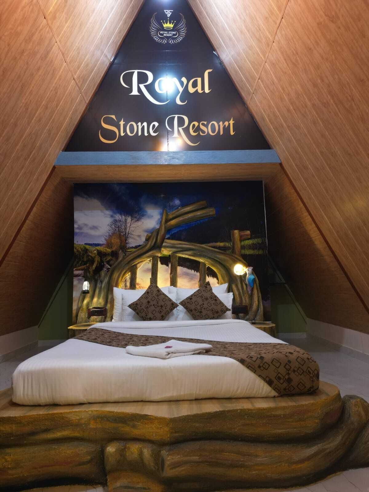 A bedroom at Royal Stone Resort with a bed, pillows, and a mural of a tree.