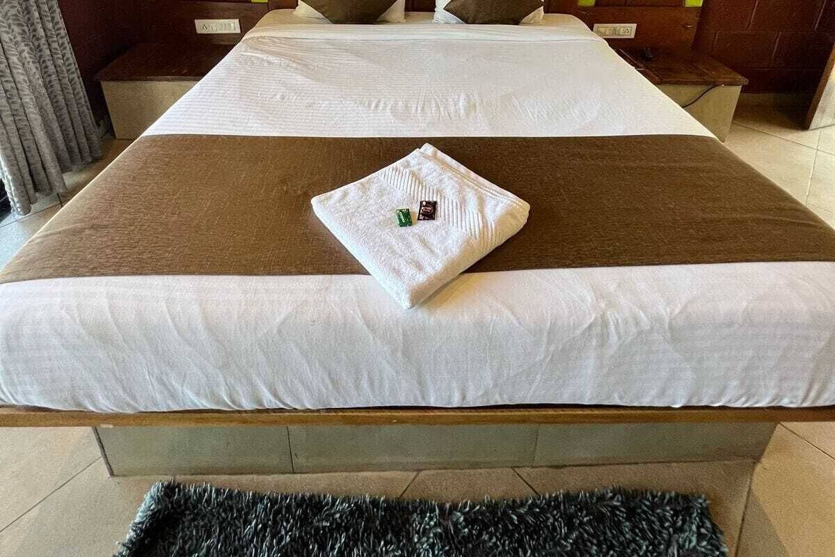 Une chambre d’hôtel avec un grand lit, des murs verts et deux lampes fixées au mur.