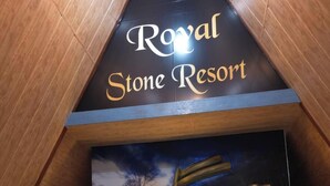 En seng i en teltlignende konstruktion med et skilt, der viser 'Royal Stone Resort'.
