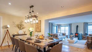 Un salón amplio con chimenea, una mesa de comedor preparada para seis personas y un gran ventanal con vistas al exterior.
