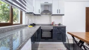 A modern kitchen with granite countertops, black cabinets, and a built-in oven.