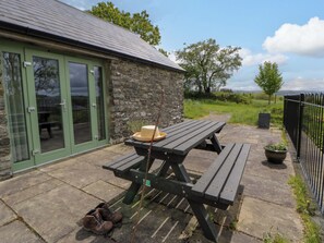 A stone building with a green door and a picnic table outside.