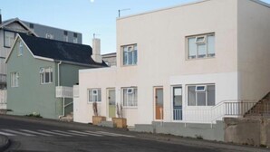 En række moderne boligbygninger med to etager, fladt tag, synlig hoveddør og lille veranda.