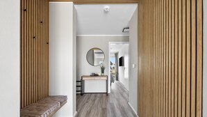 Ein moderner Flur mit einer Bank, einem runden Spiegel, einem kleinen Tisch mit Pflanze und Blick in einen weiteren Raum.