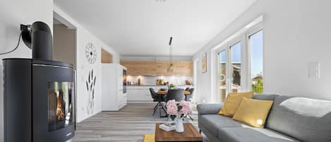 Una sala de estar moderna con chimenea, un sofá, una mesa de centro y un comedor al fondo.