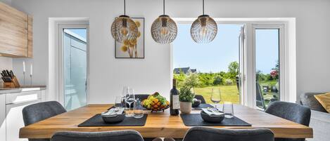 A modern dining area with a wooden table, black chairs, and pendant lights.