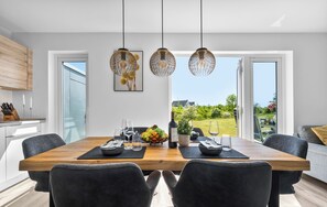 A modern dining area with a wooden table, black chairs, and pendant lights. - Vier Jahreszeiten - Terrace, Infrared Sauna, Washing Machine, Parking Space (Olpenitz)