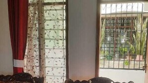 A room with two ornate sofas, a patterned rug, and a window with a view of a gated area. - Lux Suites Shiv Apartments Nyali Cinemax (Mombasa)