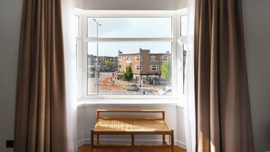 Una habitación con un ventanal grande, un banco de madera y cortinas.