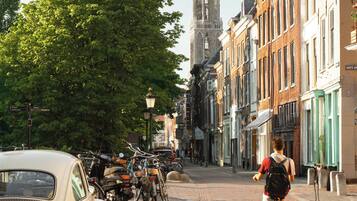 A cobblestone street lined with historic buildings, a vintage car, and a cyclist.