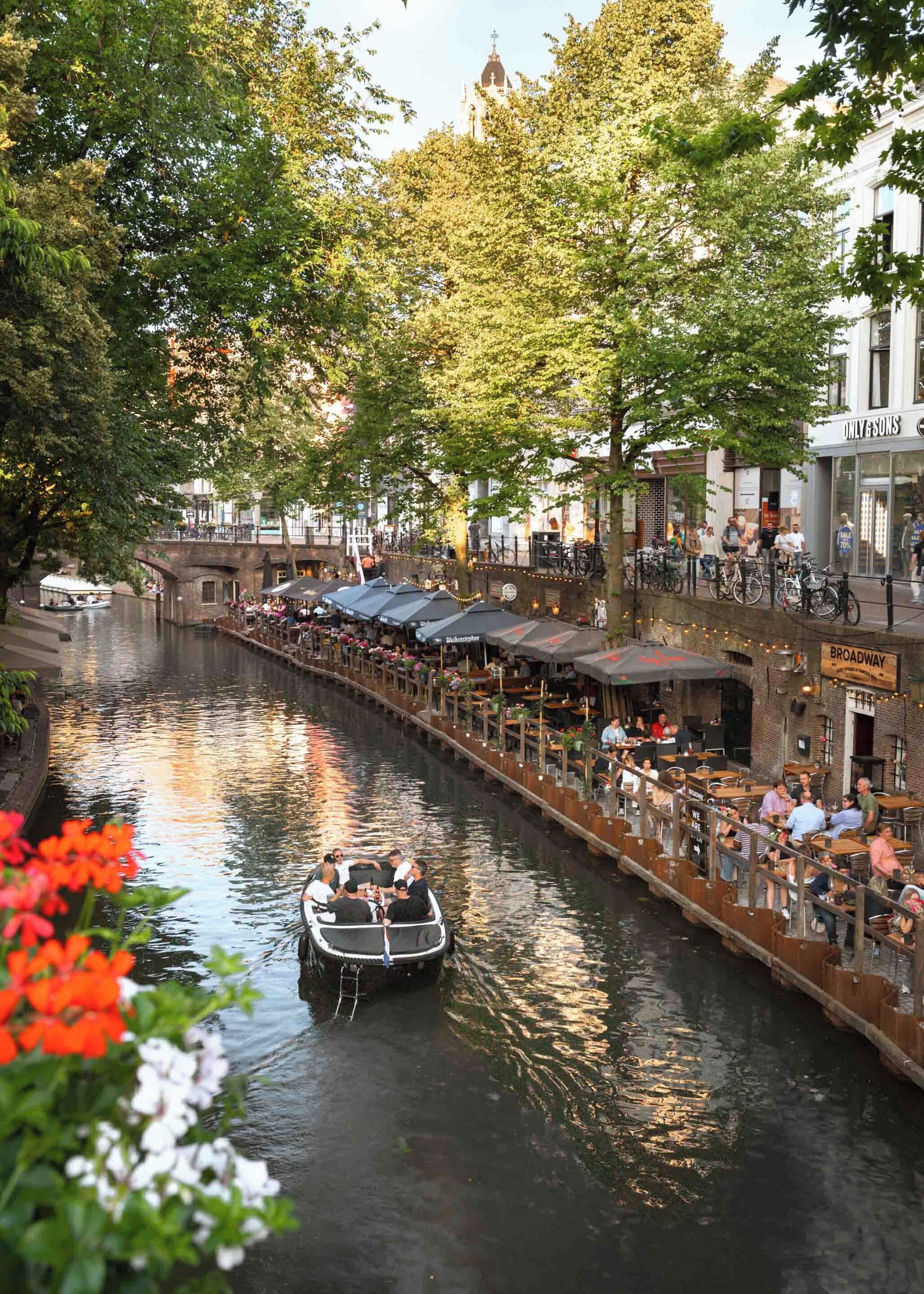 Un restaurante junto a un canal, con terraza, un bote y un puente.