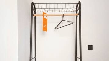A black metal drying rack with a wooden shelf and a single orange tag hanging from it.