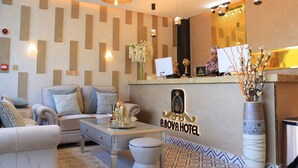 A reception area with a modern design, featuring a reception desk, seating area with sofas, and decorative elements like a vase with flowers and a tray with a Christmas tree. - Arova Hotel (Nairobi)