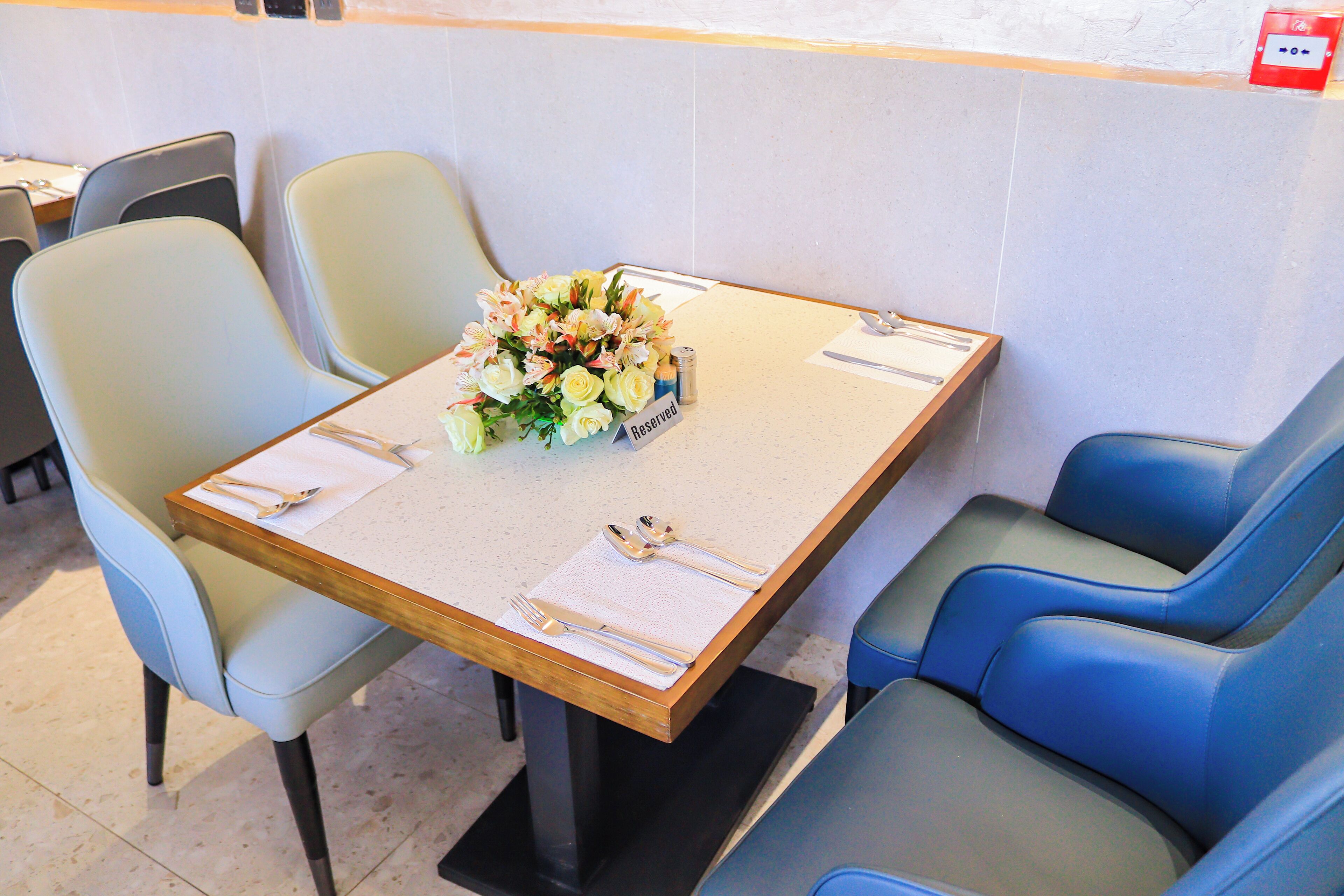 A dining area with a table set for two, a bouquet of flowers, and a 'Reserved' sign.