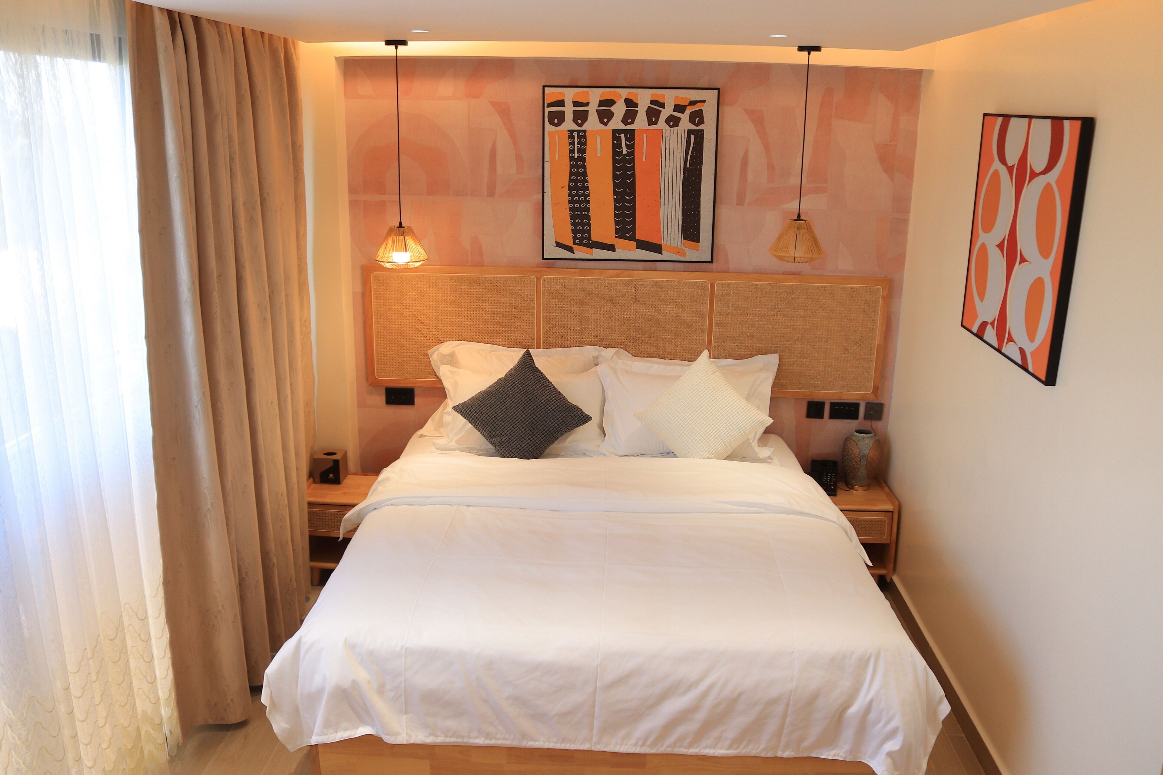 A neatly made bed with white bedding, a headboard with a woven texture, and a bedside table with a lamp and a vase.