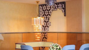 A dining area with a table set for four, a decorative wall panel, and a chandelier. - Arova Hotel (Nairobi)