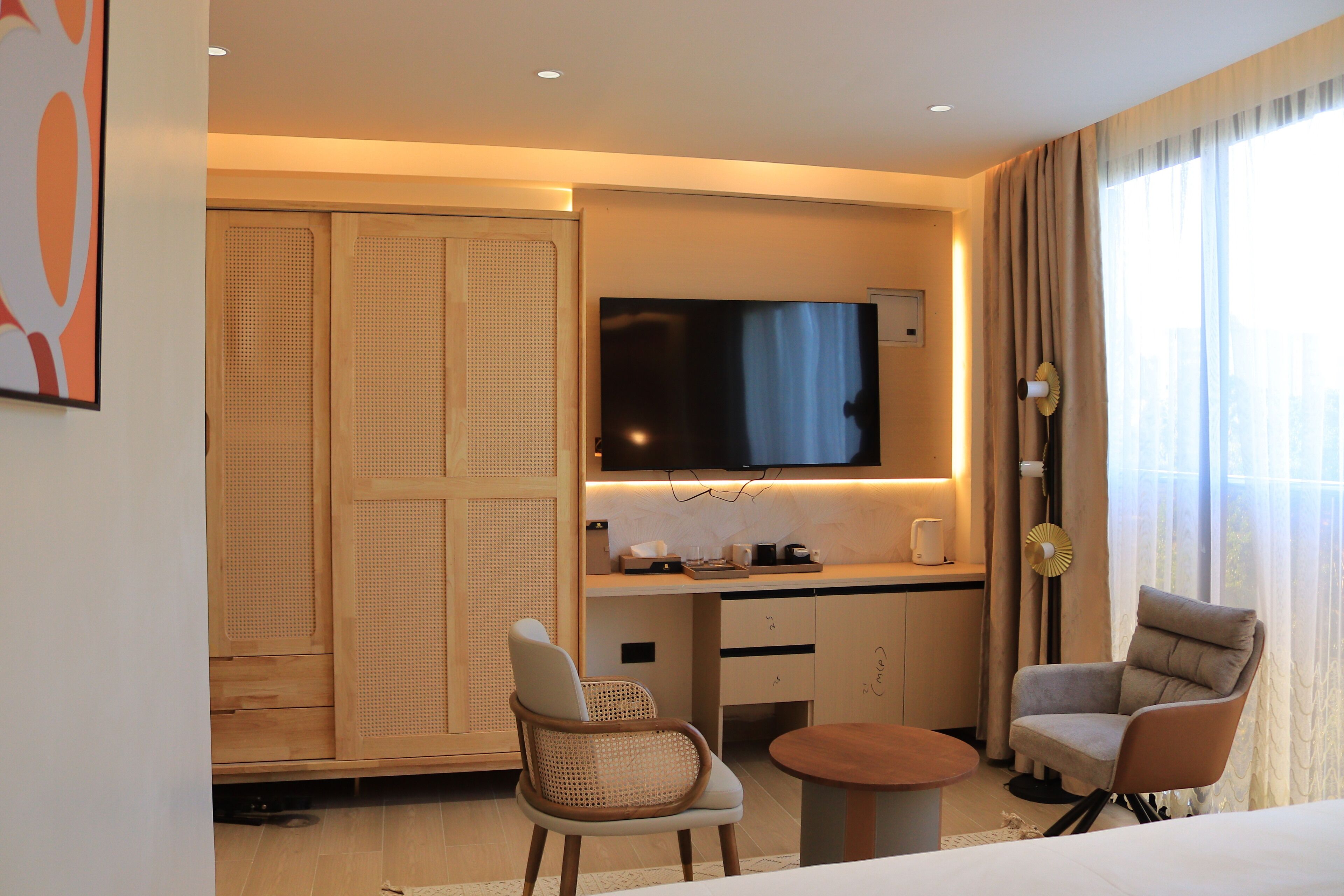 Une chambre d’hôtel moderne équipée d’un téléviseur à écran plat, d’un canapé, d’un fauteuil, d’une petite table et d’une armoire.