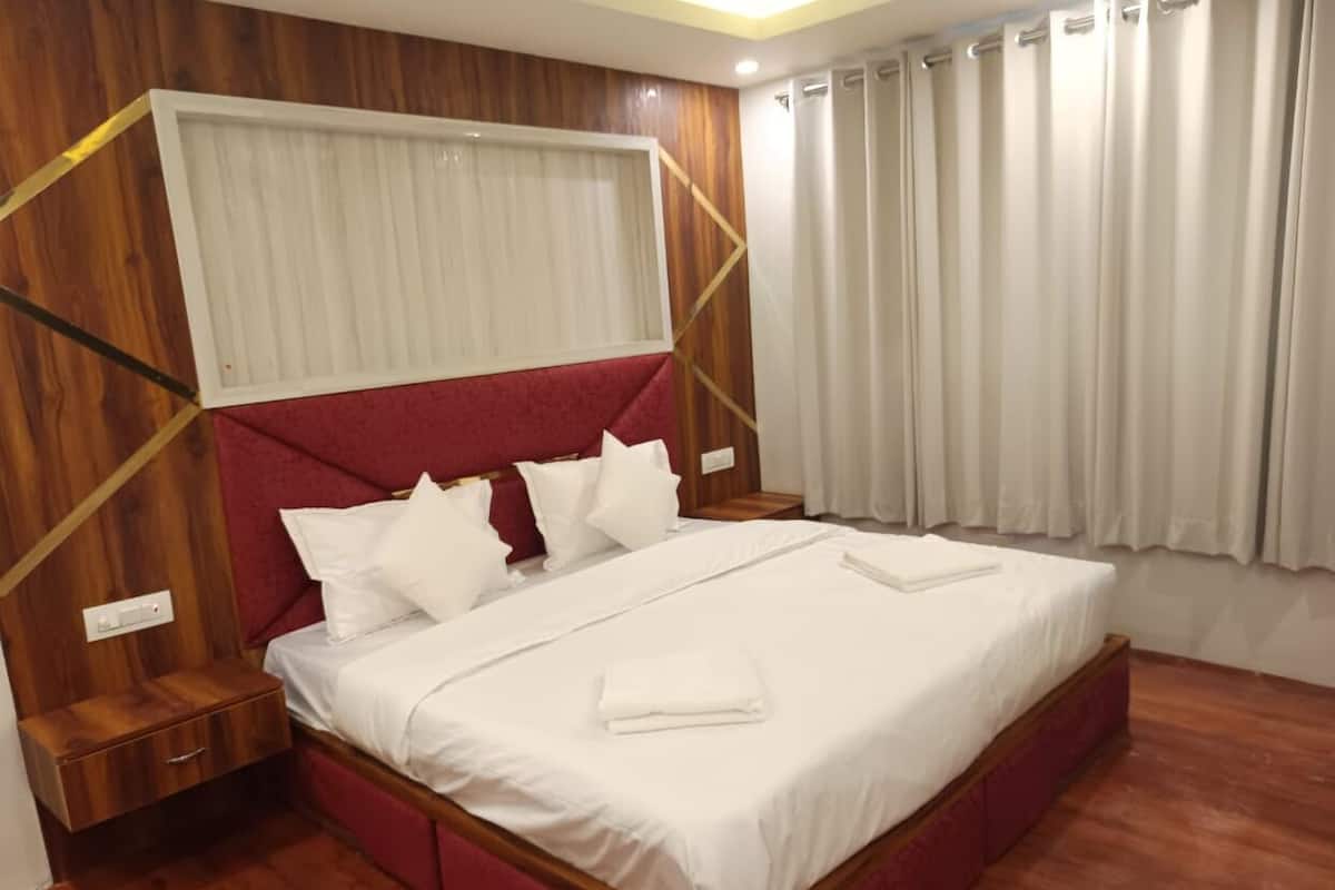 A neatly made bed with white linens and pillows, a wooden headboard, and a nightstand with a drawer.