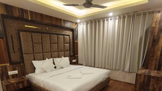 Un dormitorio moderno con una cama grande, paneles de madera en las paredes, un ventilador de techo y una ventana con cortinas.