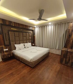 A modern bedroom with a large bed, wooden paneling on the walls, a ceiling fan, and a window with curtains. - Hotel Khyber By Angl Wings (Srinagar)