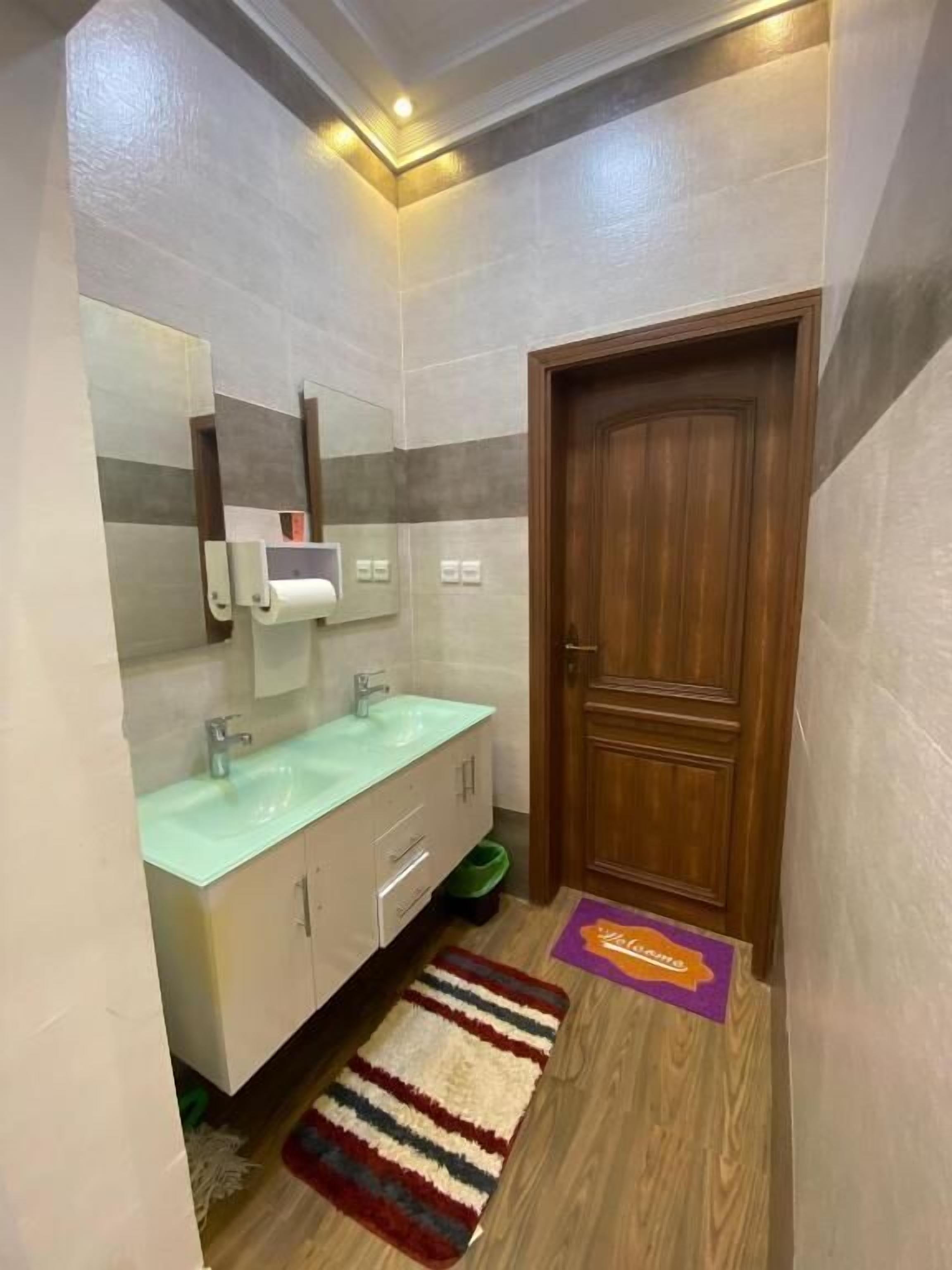 Un baño con lavabo, espejo y puerta de madera.